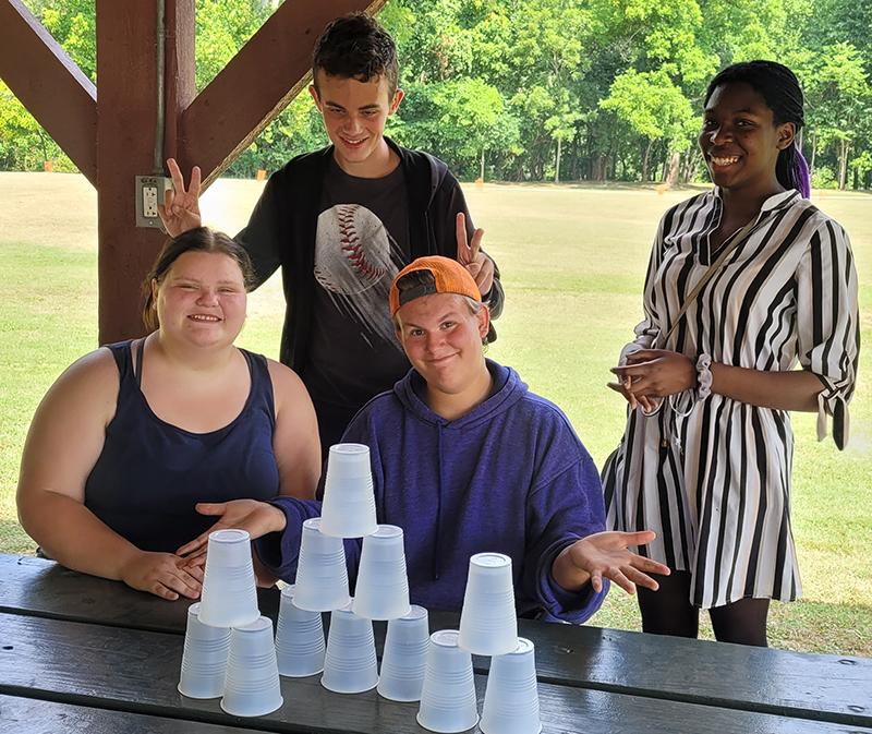 Group of people at picnic table stacking plastic cups laughing