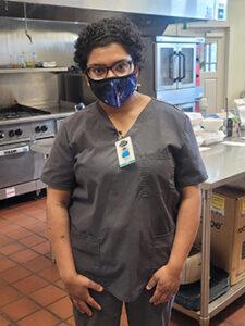 Woman with mask in restaurant kitchen working