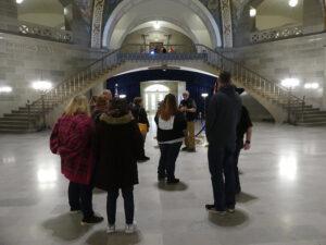 Group at museum with tour guide. Two big curvy staircases in background.