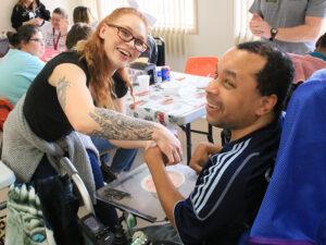 man in wheelchair and woman in glasses smiling at camera