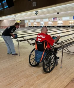 Man in wheelchair and another person bowling.