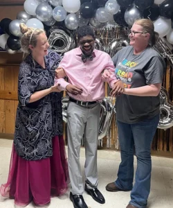 Man in bowtie with two women at a dance event.