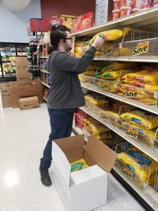 Man stocking bread at grocery store.