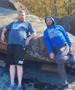 Two guys leaning up against giant rocks.