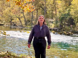 Man standing by a river and woods