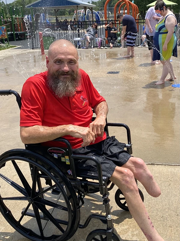 Man in wheelchair missing left foot at waterpark.