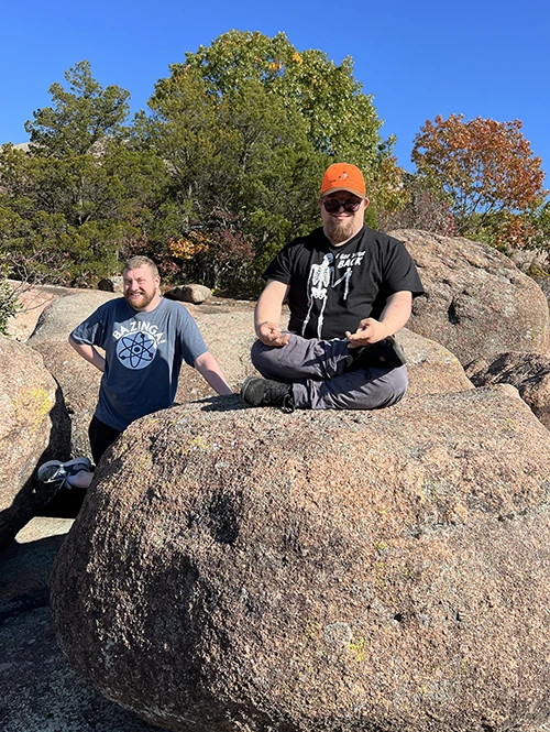 Two people sitting on stones in forest.